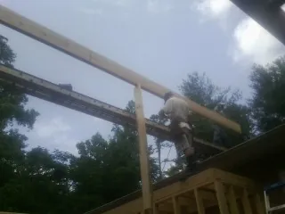 Carpenter setting a ridge beam over a new addition frame — Ice Dam Removal by Roofing Brothers in New Pine Creek