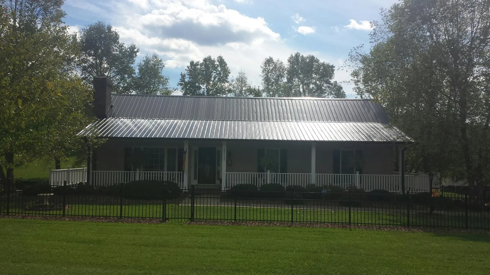 Gray metal roof on a brick ranch with a full width front porch — Gutter Guard Installation work by our crew in New Pine Creek