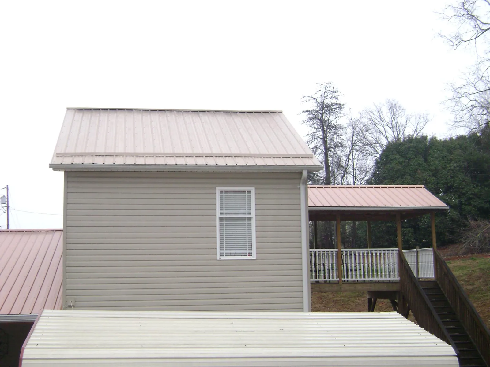 Tan metal roofs on a two story addition and attached porch, from a Roof Replacement job in New Pine Creek