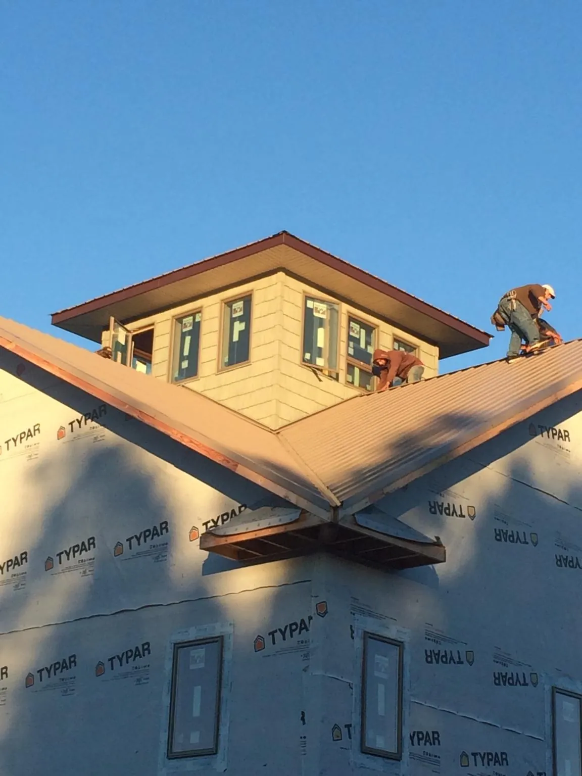Roofers working around a rooftop cupola on a new metal roof at sunset — Roof Waterproofing in New Pine Creek by Roofing Brothers